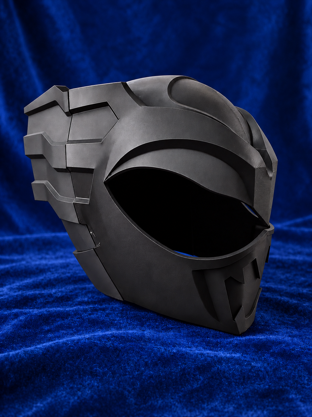 Psycho Ranger raw black PLA helmet kit on blue velvet, front three-quarter view