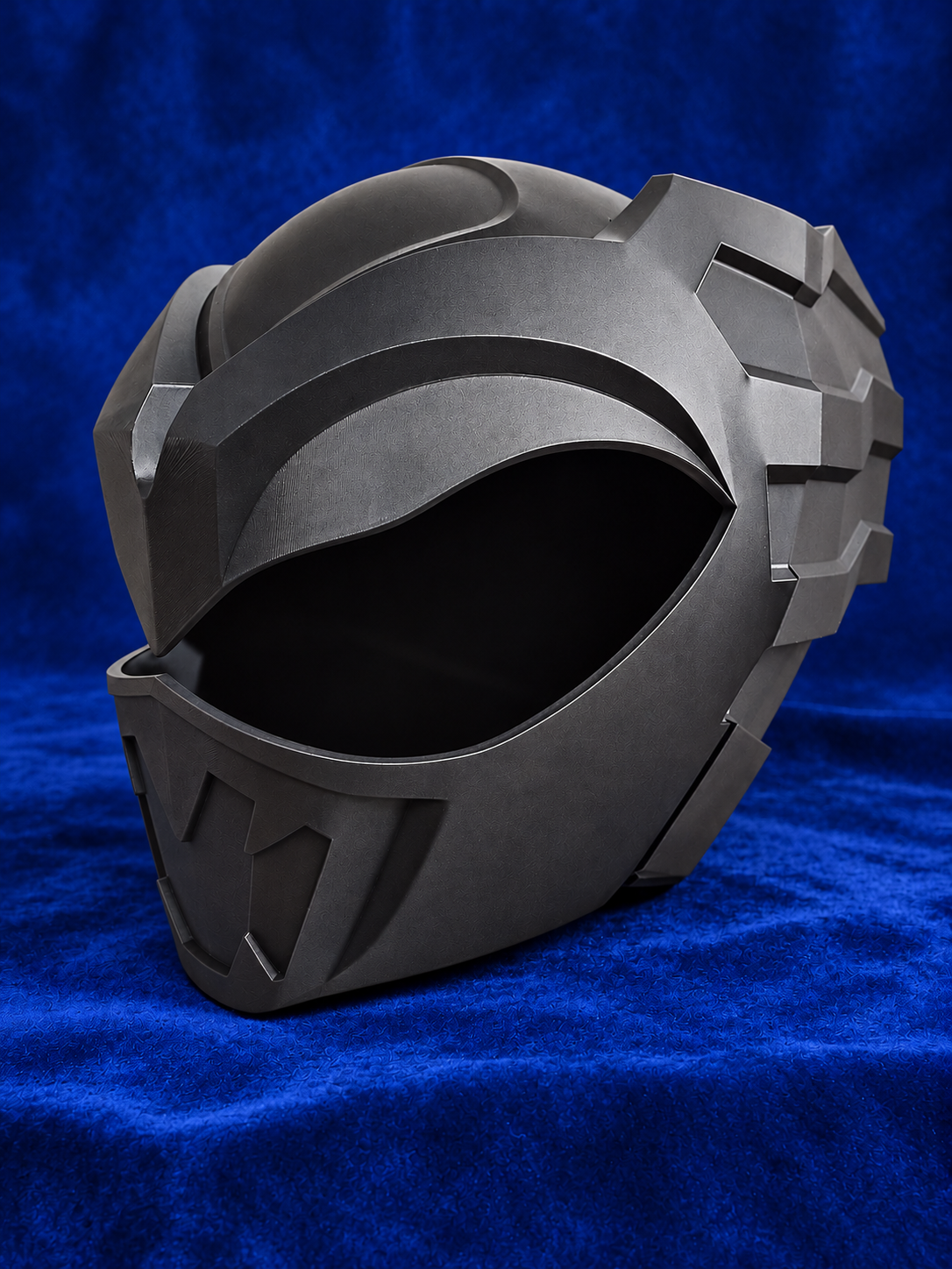 Psycho Ranger raw black PLA helmet kit on blue velvet, opposite front three-quarter view